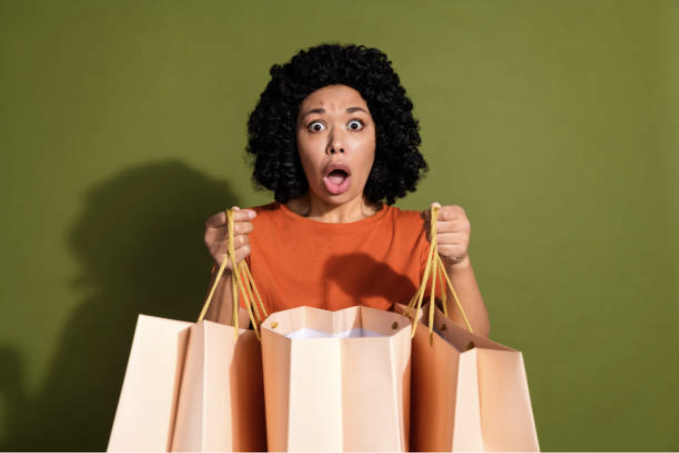 Portrait of a young woman looking upset and holding shopping bags that she regrets buying.